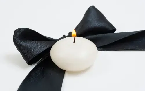 weiße Kerze auf schwarzer Seidenschleife